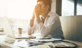 staff member sits at their desk with their head in their hands